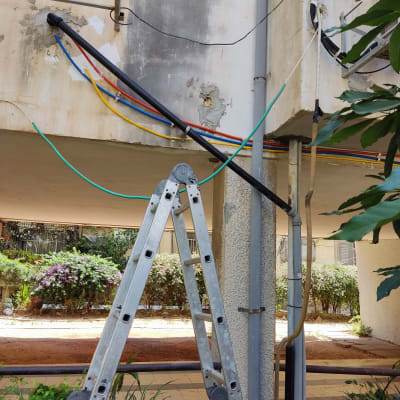 סולם מתכת ליד צינורות צבעוניים על קיר חיצוני