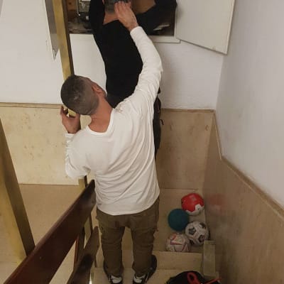 חשמלאי עובד על לוח חשמל עם פנס וכלים