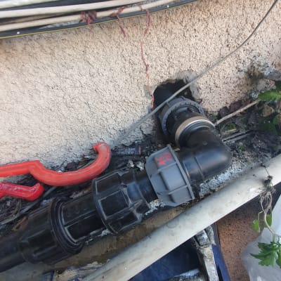 צינור פלסטיק שחור מחובר לקיר עם מחבר מתכת