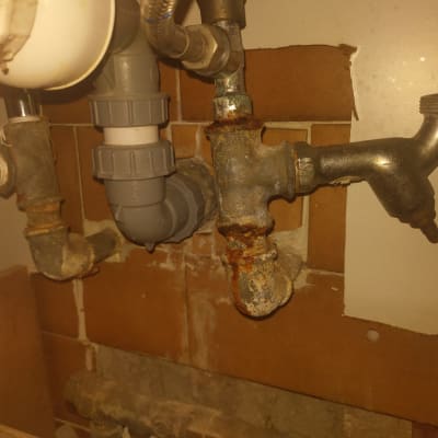 צינורות מתכת חלודים עם חיבורים מתחת לכיור