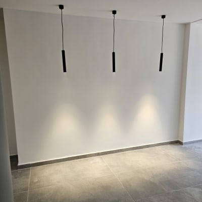 קיר לבן עם שלושה גופי תאורה תלויים