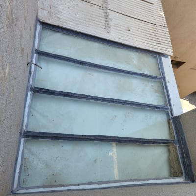 חלון זכוכית עם מסגרת מתכת על קיר בטון