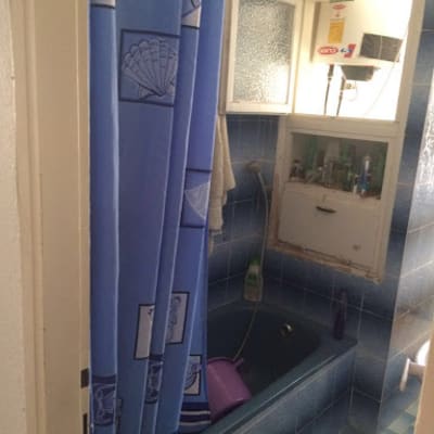 אמבטיה כחולה עם וילון מקלחת ודלת פתוחה