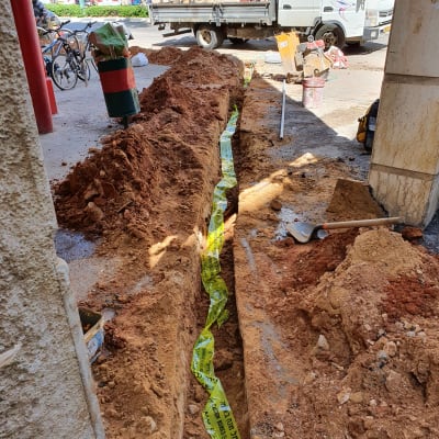 תעלה חפורה עם סרט אזהרה צהוב וכלי עבודה