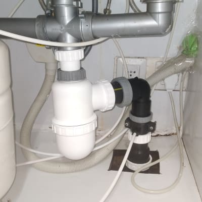 צנרת מתחת לכיור עם מחברים וצינורות פלסטיק