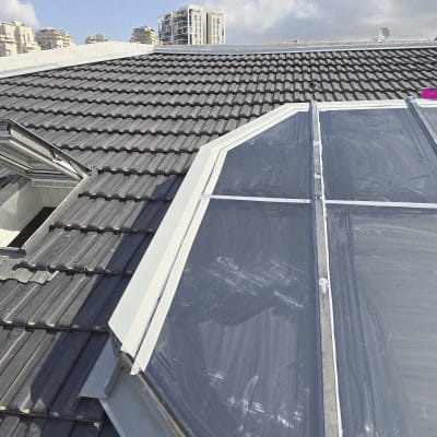 גג רעפים עם חלון זכוכית ושמים בהירים