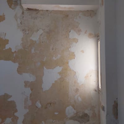 קיר מתקלף עם טיח מתפורר וכתמי צבע