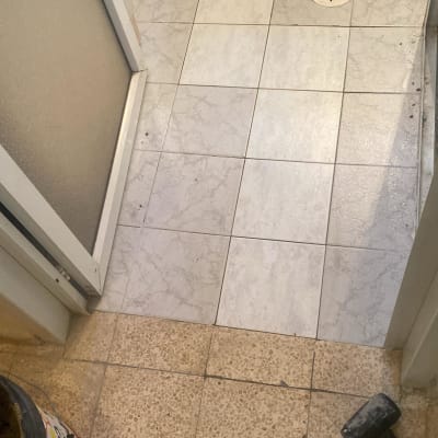 רצפת חדר אמבטיה עם פתח ניקוז ופטיש על הרצפה