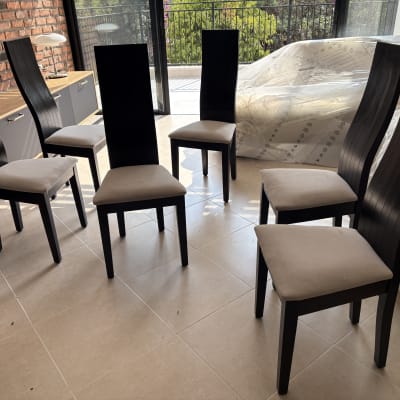 שישה כיסאות מרופדים בחדר עם קיר לבנים