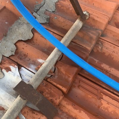 גג רעפים עם צינור כחול וסולם מתכת חלוד