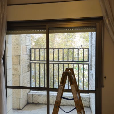 סולם וכלים ליד חלון עם תריסים