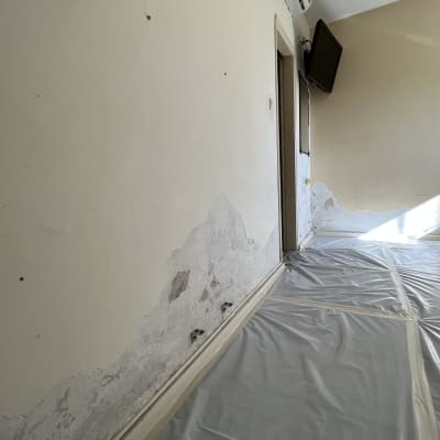 קיר עם קילופי צבע ויריעות פלסטיק על הרצפה