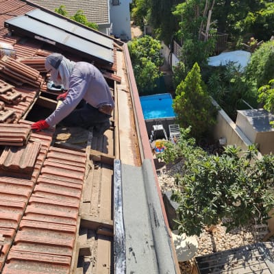 אדם מתקן רעפים על גג עם לוחות סולאריים