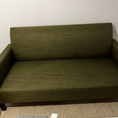 ספה ירוקה על רצפת אריחים, שולחן עם חפצים