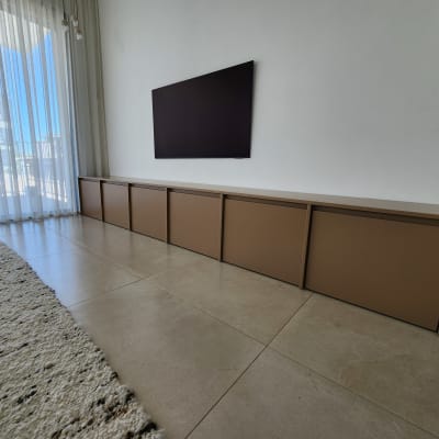 ארון עץ נמוך מתחת לטלוויזיה על קיר לבן