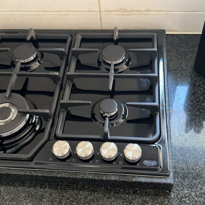 כיריים גז שחורות עם כפתורים כסופים במטבח מודרני