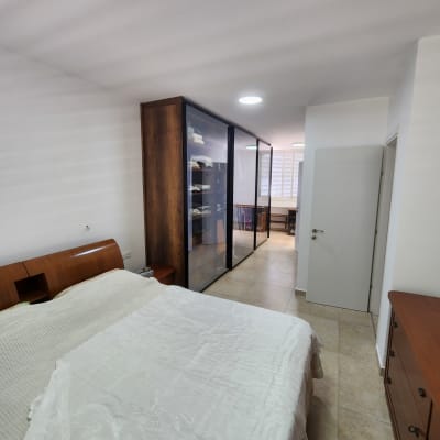 חדר שינה עם ארון בגדים ודלתות זכוכית