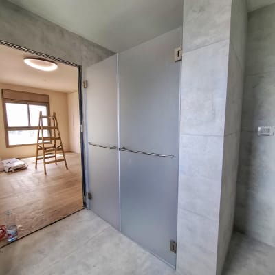 דלת זכוכית חלבית עם ידיות מתכת במקלחת