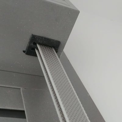 רצועת תריס אפורה מחוברת למסגרת מתכתית