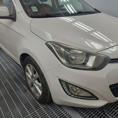 מכונית לבנה בחדר עבודה עם פנס קדמי גלוי