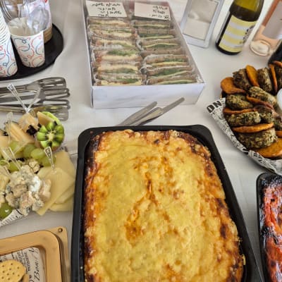 מגוון מאכלים על שולחן, כולל לזניה, כריכים, וירקות.