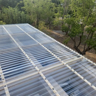 גג פלסטיק שקוף עם ברגים ועצים מסביב