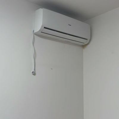 מזגן מותקן על קיר לבן עם כבל חשמל