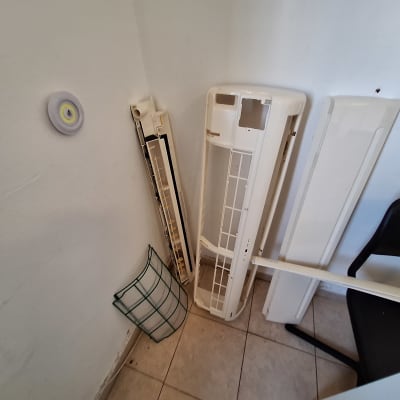 חלקי מזגן מפורקים מונחים על הרצפה ליד קיר