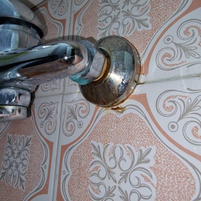 ברז מתכת עם חלודה על אריחי קרמיקה