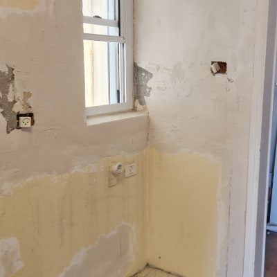 קיר עם טיח מתקלף ושקעי חשמל חשופים