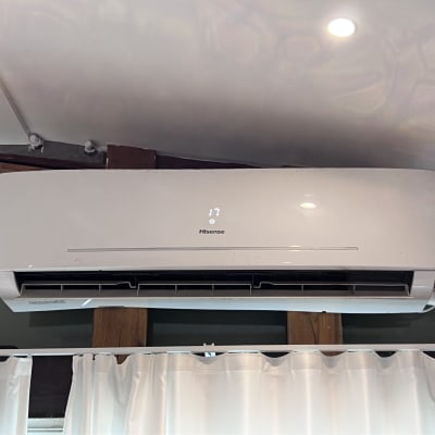 מזגן קיר לבן מותקן על קיר עם וילון לבן