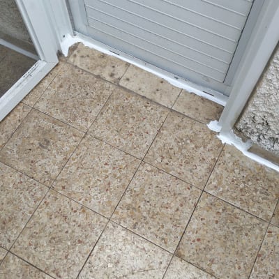 איטום עם חומר לבן בין דלת לרצפה