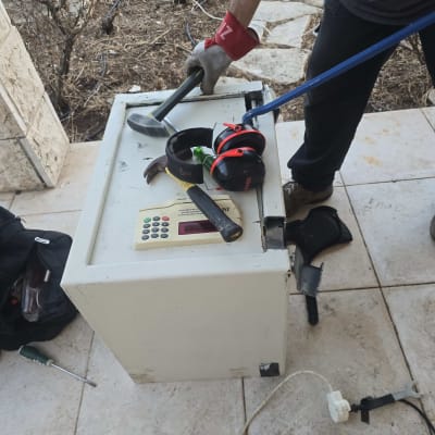 אדם עובד על כספת עם כלים שונים