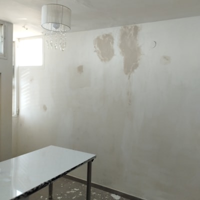 קיר עם כתמי צבע מתקלפים ושולחן עם שאריות צבע על הרצפה