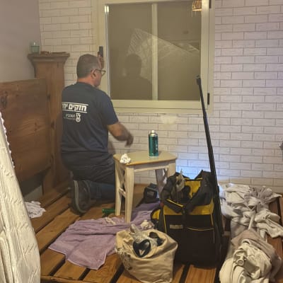 אדם מתקין תריסים בחדר עם קיר לבנים