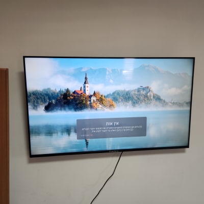 מסך טלוויזיה מותקן על קיר עם כבלים גלויים