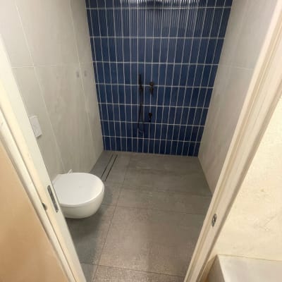 שירותים עם קיר אריחים כחולים ומקלחת מותקנת