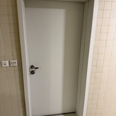 דלת לבנה עם ידית מתכת על קיר מרוצף