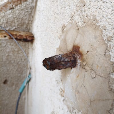 צינור חלוד בקיר עם סימני נזילה