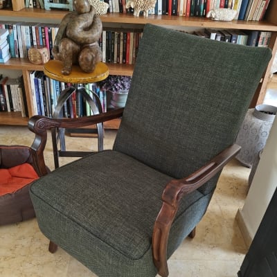 כורסה מרופדת בבד ירוק כהה עם ידיות עץ מעוצבות