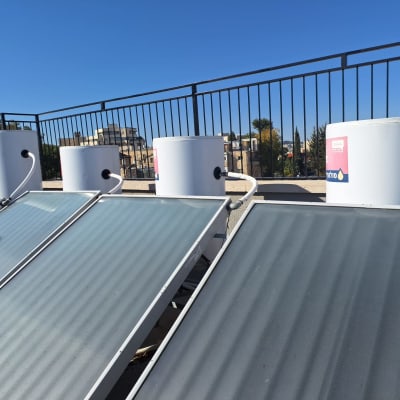 קולטי שמש ומיכלי מים על גג עם מעקה ברזל