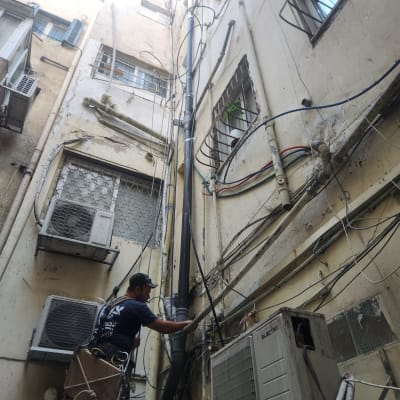 אינסטלטור עובד על צינור חיצוני בבניין גבוה