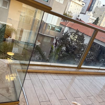 מרפסת נקייה עם רצפת עץ ומעקה זכוכית.