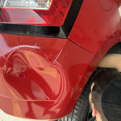 תיקון פגוש רכב אדום עם אדם עובד