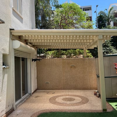 פרגולה מעץ בחצר עם צמחייה מסביב