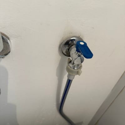 ברז מים עם ידית כחולה על קיר לבן