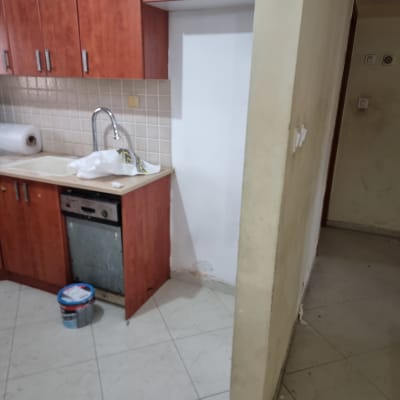 פח צבע על הרצפה ליד קיר צבוע חלקית