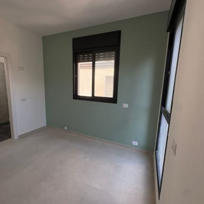 חדר ריק עם קיר צבוע ירוק וחלון
