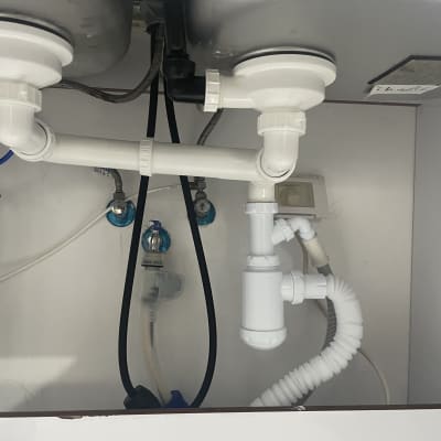 צנרת פלסטיק לבנה מתחת לכיור מטבח