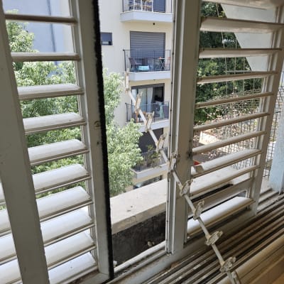 תריסים פתוחים עם נוף למרפסת בניין סמוך